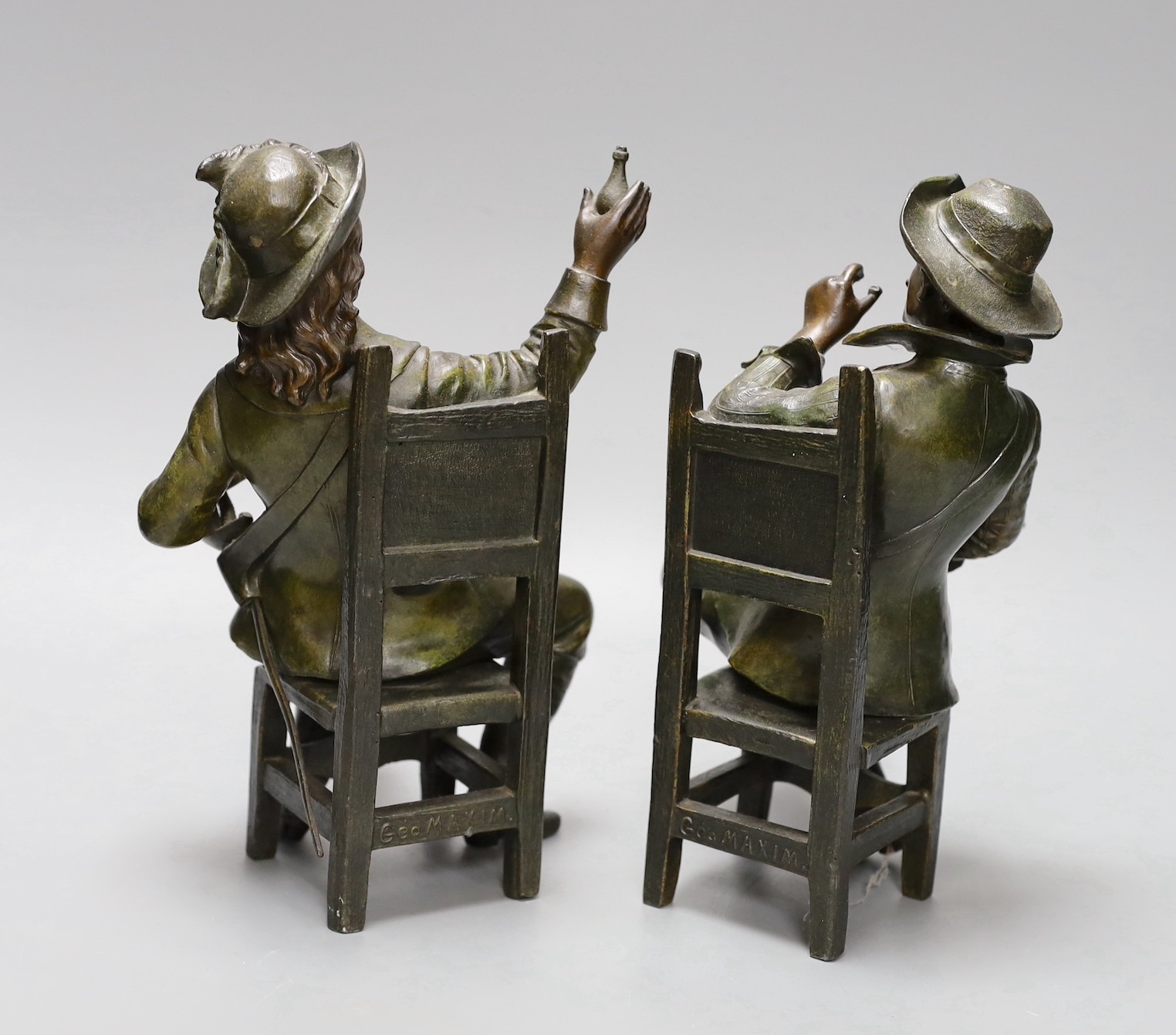 A pair of early 20th century patinated bronzed metal figures of seated cavaliers, 25 cms high